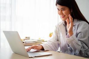 asiatisk terapeut kvinna läkare är onlinebesök med en patient på internetapplikationen. hennes lyssnande och ge råd och förklarar hur man behandlar den initiala sjukdomen, begreppet medicinsk teknik. foto