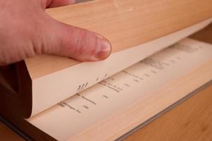 selektiv fokusvy av en gammal tjock tysk matematikbok med en manlig hand som söker i den. foto