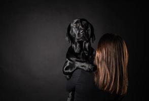 en flicka håller en labrador retrieverhund i famnen. foto