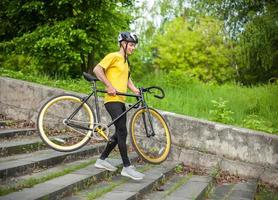 en ung man kommer ner för trappan med sin cykel i en allmän park. foto