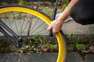 en ung man pumpar upp hjulet på sin cykel. foto