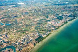 foto skott från jetplan som sköt den breda staden bredvid stranden och havet mitt i thailand.