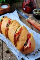 bakad baguette fylld med bacon, ost, soltorkade tomater och kapris foto