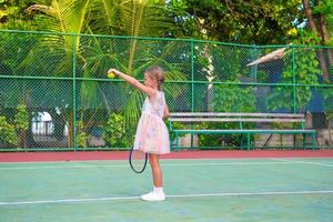 liten flicka spelar tennis på banan foto