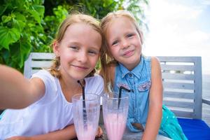 små flickor tar selfie och dricker läckra cocktails på tropical resort foto