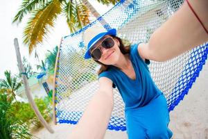 vacker kvinna gör selfie avkopplande vid hängmattan foto