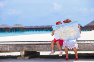 bedårande små flickor med karta över ön på stranden foto