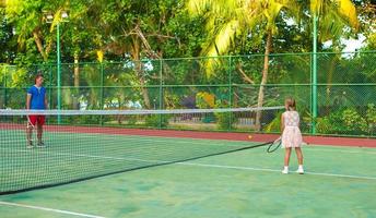 liten flicka spelar tennis med sin pappa på banan foto