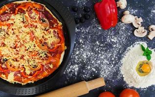 rå pizzadeg med ingredienser och kryddor på mörk bakgrund. toppvy foto
