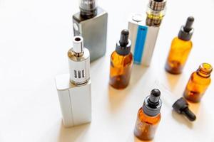 vaping enhet e-cigarett elektronisk cigarett och vätskeflaskor isolerad på vit bakgrund. vapeapparat för alternativ rökning. vaping butik koncept. pryl för vaper. vaping tillbehör. foto