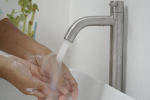 kvinna som använder tvål och tvättar händerna under kranvatten. foto