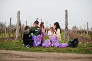 familj med soppåse som samlar sopor medan de städar i vingårdarna. miljövård och ekologi, återvinning. foto