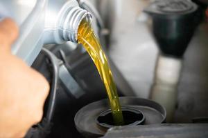 hälla motorolja till bilmotorn. färsk olja som hälls under ett oljebyte till en bil. foto