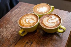 latte kaffe eller cappuccino kaffe i vit kopp med vacker träd latte konst på träbord. foto