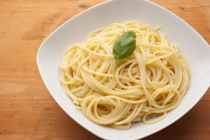 spaghetti med basilika på plattan på trästruktur