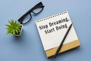 motiverande och inspirerande citat på anteckningsblocket - sluta drömma, börja göra. foto