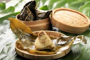 zongzi eller bakcang, kinesiska salta klibbiga risdumplings i bambubladsomslag. färskt koncept med färska bakcang blad. foto
