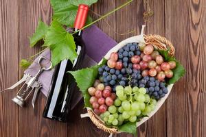 rött vinflaska och färgglada druvor foto