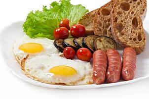 engelsk frukost - stekt ägg, korv, aubergine och tomater foto