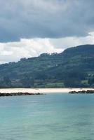 vertikal bild av Rodiles-stranden sett från el puntal, på andra sidan floden. plats för fågelskådning. asturien. foto