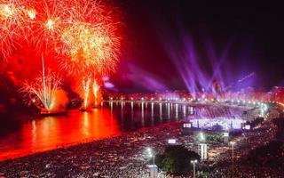 festglada, både lokalbefolkningen och turister, njut av det hisnande nyårsfyrverkeriet längs stranden Copacabana, Rio de Janeiro, Brasilien foto