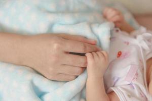 asiatisk nyfödd baby håller mödrar hand foto
