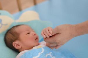 asiatisk nyfödd baby håller mödrar hand foto