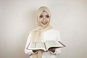 ung asiatisk muslimsk kvinna som ler och håller i koranen foto