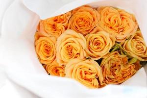 orange vacker ros insvept i papper till försäljning på blomstermarknaden, presentpresent på alla hjärtans dag. foto