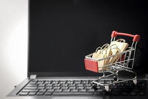 vagn med shoppingkassar på laptop tangentbord. online shopping, elektronisk handel och köpa varor från säljare över internet koncept foto