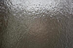 fruset vatten på fönstret. genomskinligt glas med is är genomskinligt, underkylt regn. bilvindruta efter regn - trafiksäkerhet på vintern, ingen sikt. bakgrund foto