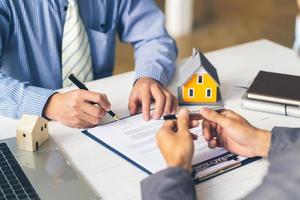 fastigheter hem pekar på försäkringsavtal undertecknande och förklarar för kunder på kontoret. hus byrå koncept. foto