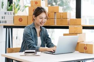 ungt företag startar upp online säljare ägare som använder dator för att kontrollera kundens beställningar från e-post eller webbplats och förbereda paket för produkt kontorsutrustning. foto