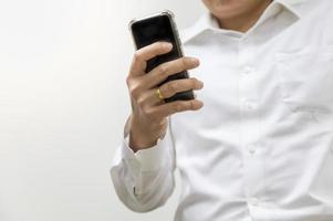 asiatisk affärsman som bär vit skjorta som håller en smart mobiltelefon på vit bakgrund med kopia utrymme. foto