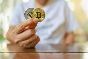 affärs-, pengar-, teknik- och kryptovalutakoncept. närbild av man hand som håller guld och silver bitcoin-mynt på träbord. foto