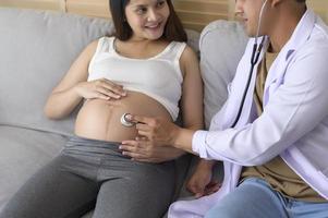 en läkare som håller stetoskop undersöker en gravid kvinna på sjukhuset, sjukvården och graviditetsvårdskonceptet foto