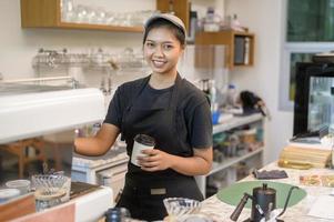 ung serviceinriktad baristakvinna som arbetar i kafé foto