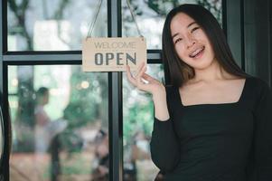 kvinna som står med öppen skylt, öppen butik foto