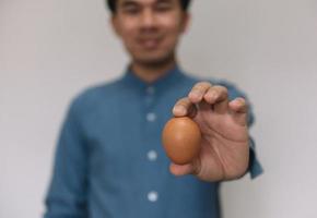 manlig hand som håller påskbrunt kycklingägg isolerad på grå bakgrund foto