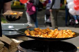 bitar av stekt potatis i en stor stekpanna under street food festivalen. foto