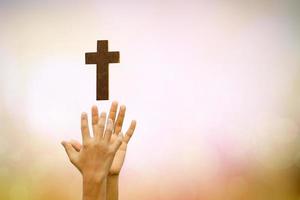 mänsklig hand som håller kors på suddig naturbakgrund. foto