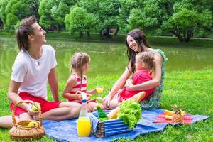 glad ung familj som picknick utomhus nära sjön foto