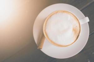 ovanifrån av varm kaffe cappuccinokopp med mjölkskum på träbord foto