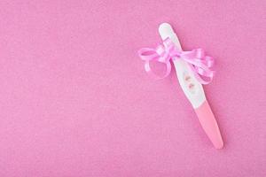 positivt graviditetstest isolerad på rosa bakgrund foto