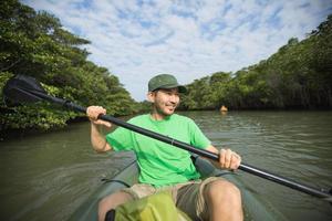 man njuter av flodkajakpaddling i mangroveskogen, Japan foto