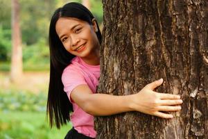 asiatiska kvinnor omfamnar träd med kärlek, begreppet kärlek till världen foto