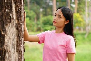 asiatiska kvinnor omfamnar träd med kärlek, begreppet kärlek till världen foto