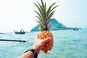 sommarananas, ananas i handen på en båt till havs foto