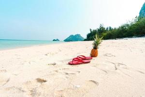 sommarstrandsemester med ananas och flip flops på stranden foto