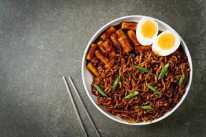 jjajang rabokki - koreanska snabbnudlar eller ramyeon med koreansk riskaka eller tteokbokki och ägg i svart bönsås foto